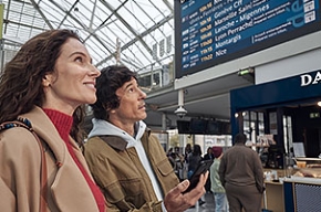 Photo d'un couple regardant le tableau des gares